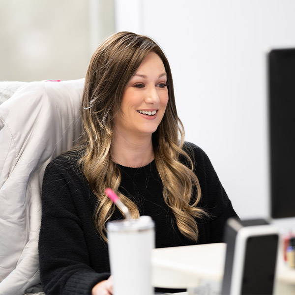 A woman is sitting at a desk in front of a computer